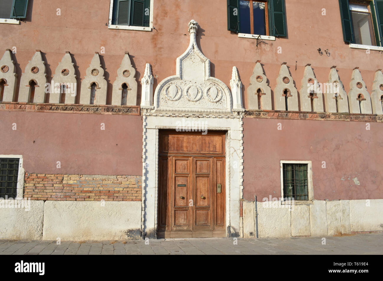 Vue de la façade d'une ancienne maison en bois avec grande porte principale à la Venise italienne front de mer de la lagune de Venise illuminée par la lumière du soleil. Banque D'Images