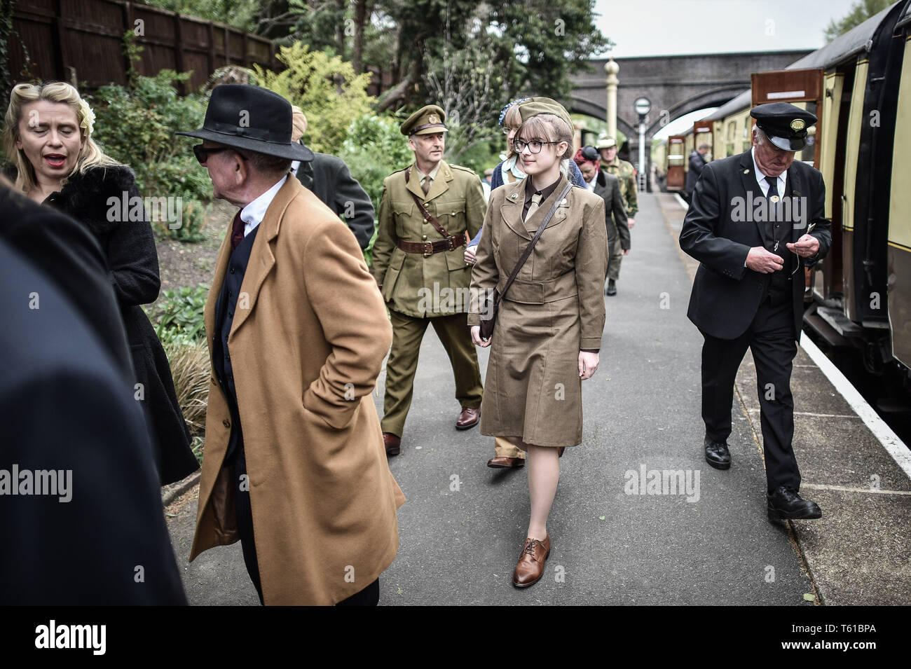 Des gens habillés en uniforme d'ÉPOQUE DE LA DEUXIÈME GUERRE MONDIALE à pied le long de la plate-forme à Toddington pendant la guerre dans la région des Cotswolds Gloucestershire au chemin de fer à vapeur du Warwickshire. Banque D'Images