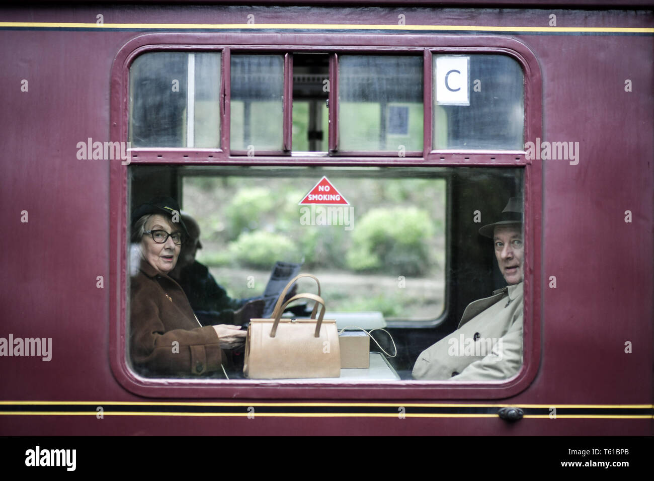 Des gens habillés en uniforme d'ÉPOQUE DE LA DEUXIÈME GUERRE MONDIALE S'asseoir dans un train à Toddington pendant la guerre dans la région des Cotswolds Gloucestershire au chemin de fer à vapeur du Warwickshire. Banque D'Images
