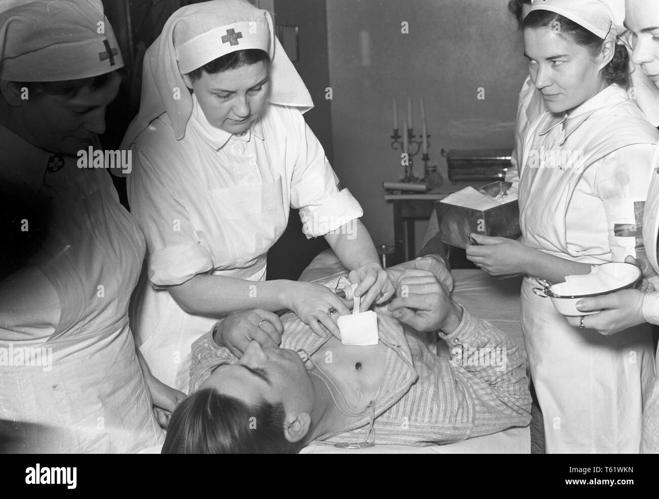 La guerre d'hiver. Un conflit militaire entre l'Union soviétique et la Finlande. Il a commencé par une invasion soviétique en novembre 1939 lors de l'infantery soviétique ont franchi la frontière sur l'isthme de Carélie. Ici l'intérieur de l'hôtel Pohjanhovi Rovaniemi en Finlande. Pendant la guerre il est en partie transformé en hôpital militaire. Une équipe d'infirmières tendent à un homme qui a coup de fusil blessure. Janvier 1940. Kristoffersson Photo ref 97-12 Banque D'Images