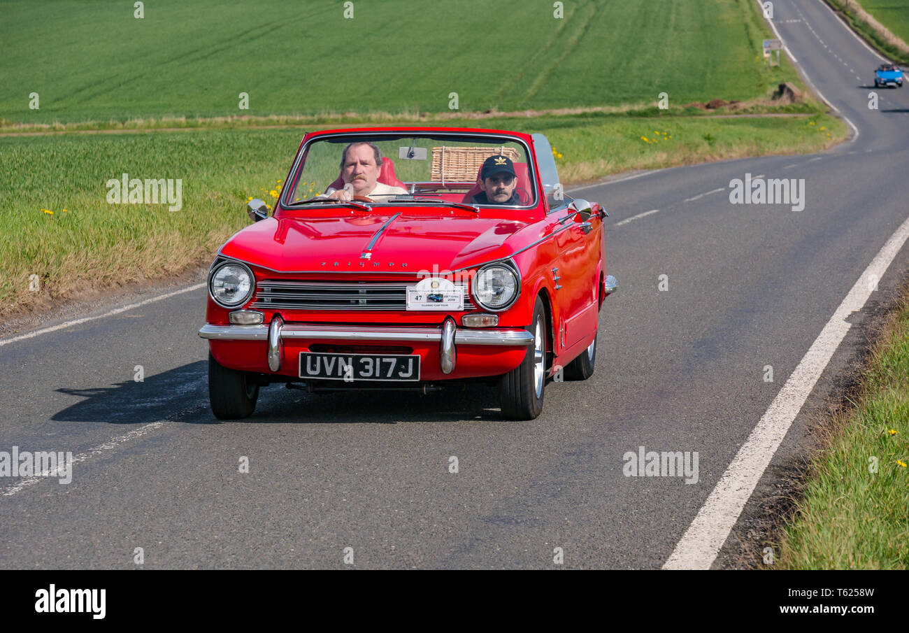 East Lothian, UK. 28 avril 2019. Voiture Classique Tour : North Berwick Rotary Club organise son 3ème rallye avec 65 voitures inscrites. La voiture parcours est de East Lothian et retourner par le Scottish Borders, la collecte de fonds pour les organismes de bienfaisance locaux. Un rouge vintage 1970 Triumph Herald convertible sur une route de campagne Banque D'Images