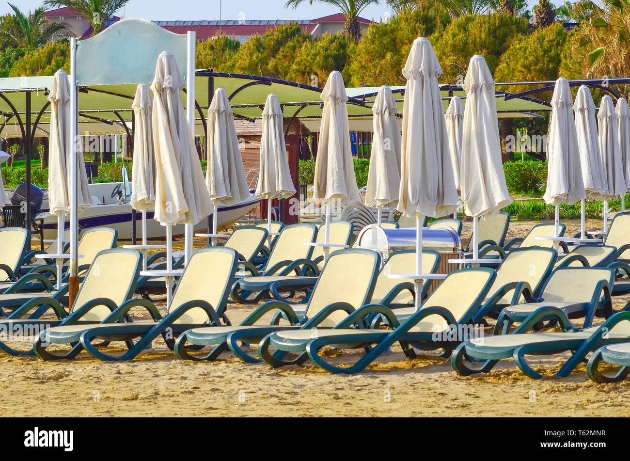 Des chaises vides et fermées des parasols sur une plage de sable Banque D'Images