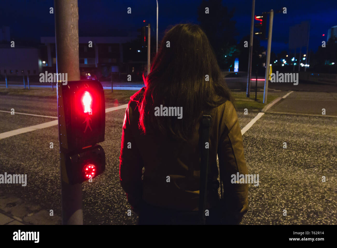 Jeune fille en attente de traverser une rue de nuit lumière rouge brille Banque D'Images