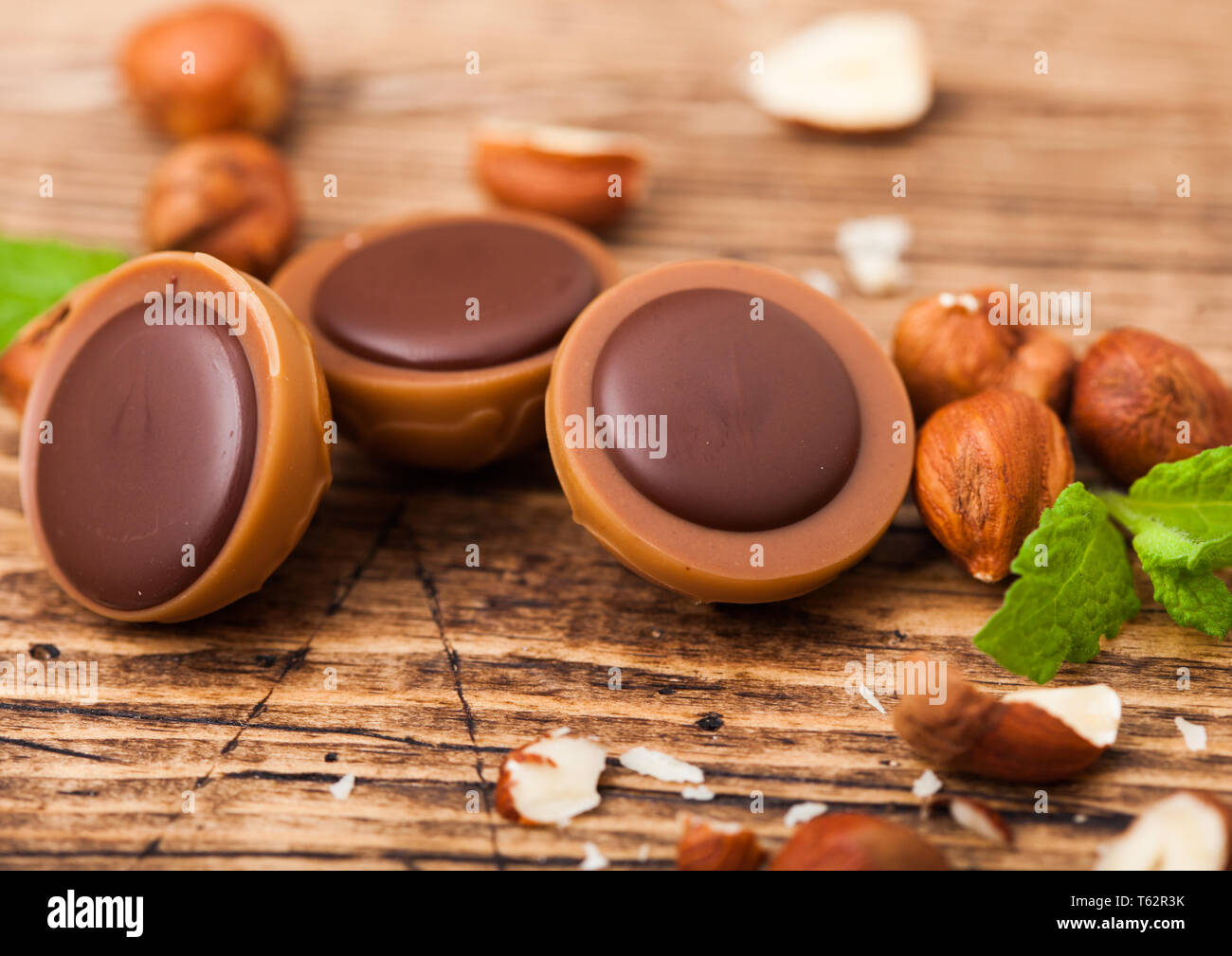 Fort des bonbons faits maison sur fond de bois avec feuille de menthe et d'écrous. Une noisette de caramel et chocolat. Banque D'Images