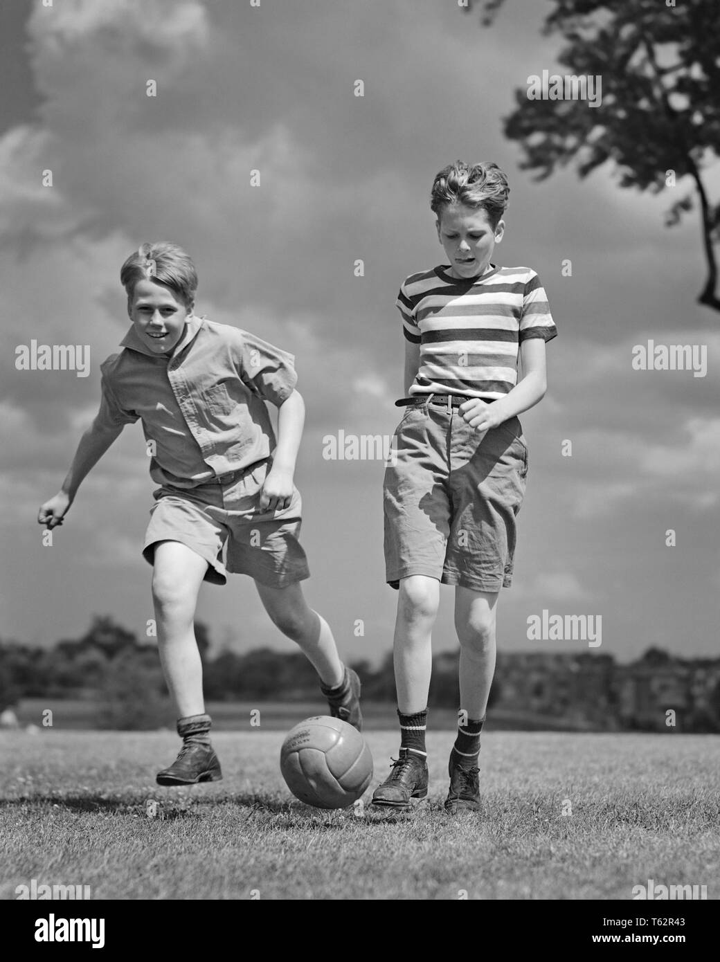 1940 DEUX PRETEEN BOYS à l'extérieur portant des shorts et baskets à l'exécution des coups de ballon de soccer - b10357 HAR001 VITESSE HARS SANTÉ RURAL COUPS DE COPIER TOUTE LA LONGUEUR DE L'AMITIÉ L'ESPACE DE REMISE EN FORME PHYSIQUE ATHLÉTIQUE HOMMES SNEAKERS CONFIANCE B&W le bonheur de l'activité de loisirs physiques et de l'EXCITATION STRATÉGIE FORCE LOW ANGLE PRETEEN FLEXIBILITÉ CONCEPTUELLE ÉLÉGANTE MUSCLES MINEURS PRÉ-ADO PRÉ-ADO GARÇON NOIR ET BLANC DE L'ORIGINE ETHNIQUE CAUCASIENNE HAR001 old fashioned Banque D'Images