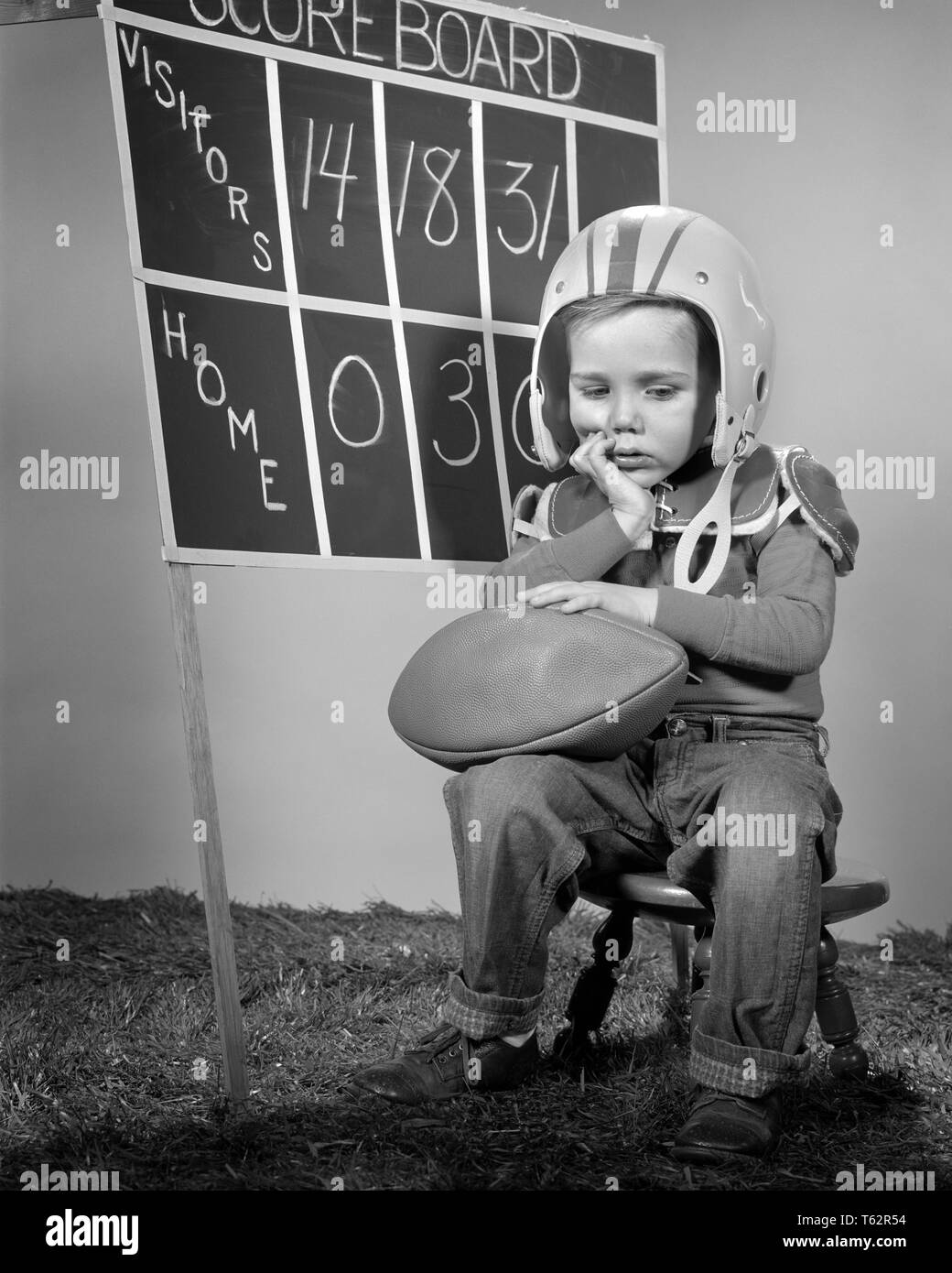 1960 DÉCOURAGÉE BOY WEARING HELMET ET PLAQUETTES HOLDING FOOTBALL ASSIS EN FACE DE L'ÉQUIPE D'ACCUEIL TABLEAU DE BORD - b1098 DÉFAIT HAR001 HARS VIEILLE NOSTALGIE DU TEMPS 1 OLD FASHION STYLE VISAGE JUVÉNILE CONCURRENCE PERDU SCORE pleine longueur de vie de l'athlète d'ATHLÉTISME HOMMES B&W TRISTESSE EXPRESSIONS TABLEAU DE PROTECTION ET DE LEADERSHIP CATASTROPHE FIERTÉ PLAQUETTES AVANT DE PERDRE EN CONCEPTUEL BEAT TRISTE ÉMOTION ÉMOTIONS JUVÉNILES CROISSANCE ÉMOTIONNELLE SAISON MISÉRABLE NOIR ET BLANC DE L'origine ethnique caucasienne défait HAR001 old fashioned Banque D'Images