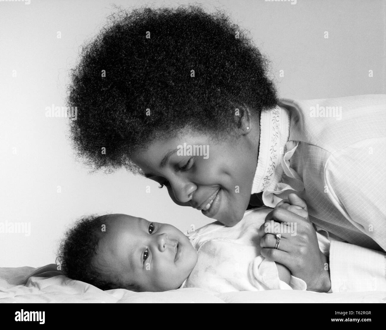 1970 SMILING AFRICAN AMERICAN MOTHER HOLDING MAIN ET REGARDANT HAPPY BABY fille allongée sur le dos - b24811 HAR001 HARS ANCIENNE MODE 1 JEUNES ADULTES DU VISAGE JUVÉNILE FORT HEUREUX JOIE INFANTILE SANTÉ FEMMES VIE DE LA VIE DE FILLES PERSONNES INSPIRATION PRENDRE SOIN SÉRÉNITÉ EXPRESSIONS CONFIANCE B&W LE BONHEUR DE LA TÊTE ET DES ÉPAULES LA FORCE JOYEUSE africains-américains africains-américains et la fierté à l'ORIGINE ETHNIQUE NOIRE SUR SMILES AFFECTION ATTACHEMENT PERSONNEL élégant joyeuse émotion juvéniles CROISSANCE MAMANS TOGETHERNESS WOMAN STYLE CHEVEUX NOIR ET BLANC bébé fille HAR001 old fashioned Banque D'Images