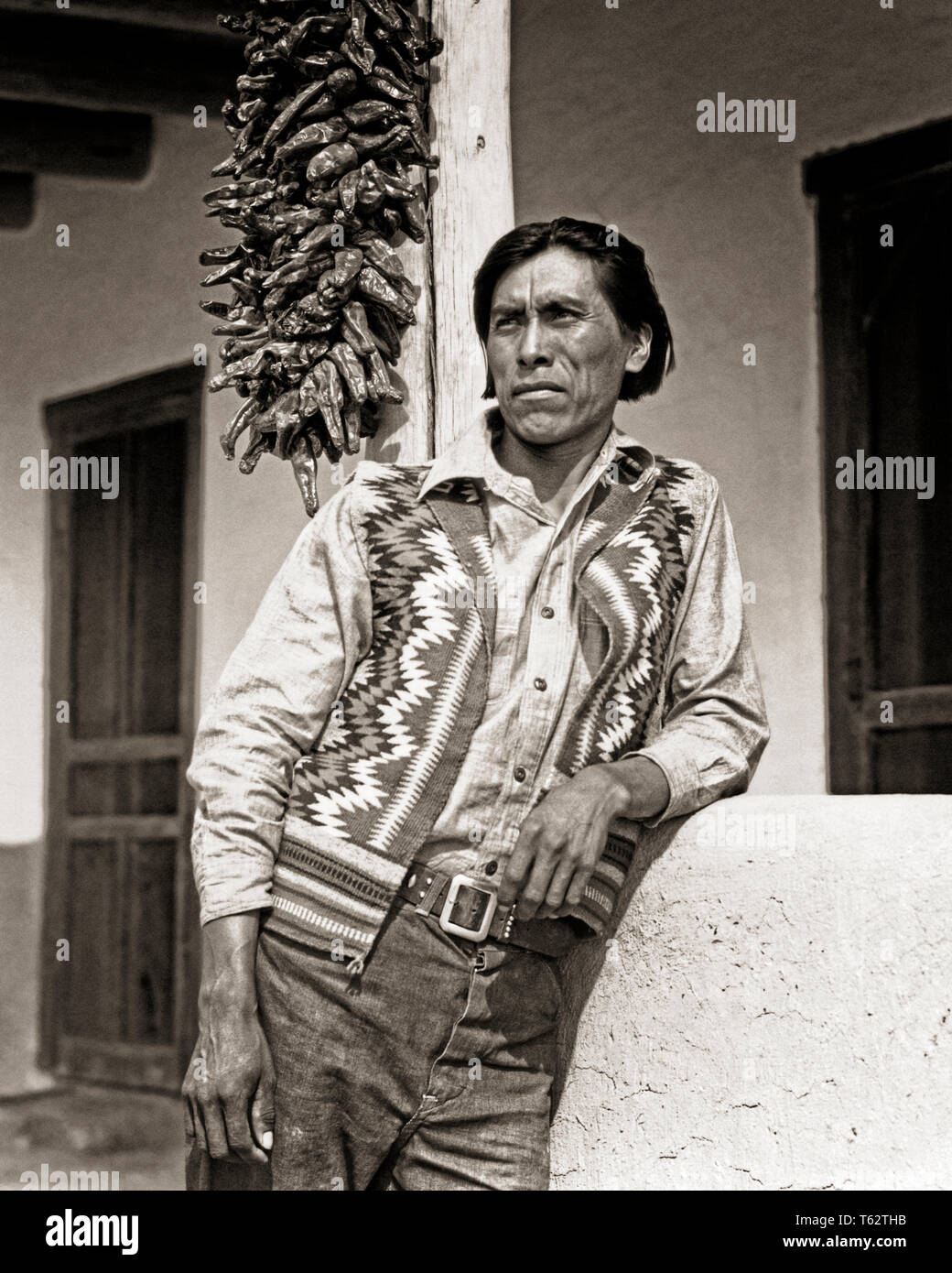 PORTRAIT 1930 Native American Indian homme portant un gilet tissé extérieur  permanent ACCUEIL ADOBE PUEBLO SAN ILDEFONSO NOUVEAU MEXIQUE USA - i3042  HAR001 AMÉRIQUE DU NORD SÉCHÉ H.A.R.S. FORCE FIERTÉ NATIVE AMERICAN