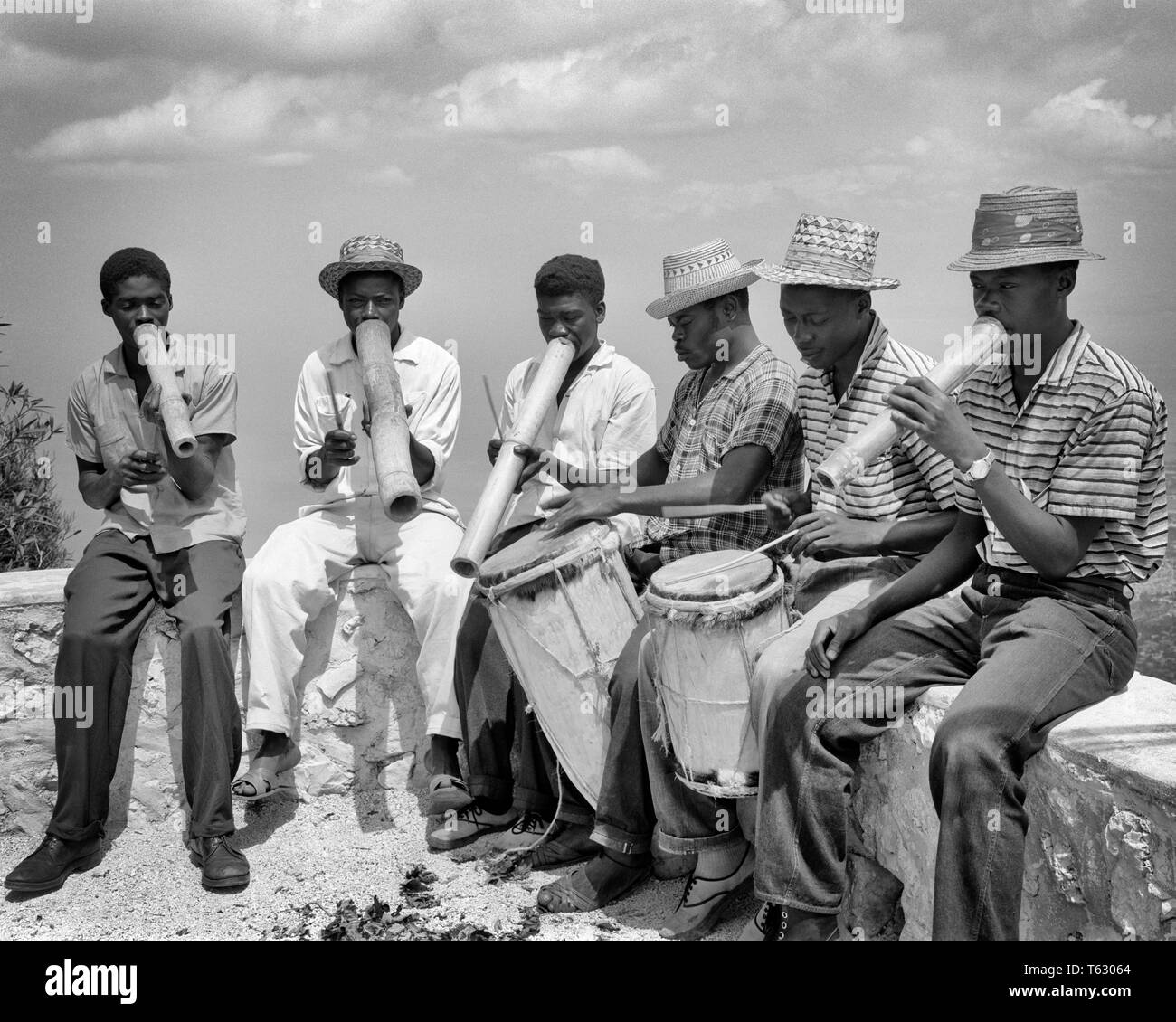 Groupe des années 1960 des musiciens haïtiens natifs anonyme jouant des instruments fabriqués à la main assis sur un mur extérieur - r17196 FIL001 HARS 6 fûts Communiquer Personnes HOMMES CARAÏBES PROFESSION SIX CORNES B&W DIVERTISSEMENT COMPÉTENCES COMPÉTENCES PROFESSION MUSICIENS MINORITAIRES MANUEL INSTRUMENT DE PERCUSSION PERCUSSION INTERPRÈTE CARRIÈRES DE LA DIVERSITÉ ETHNIQUE SUR LES PROFESSIONS ARTISTE MUSICAL INSTRUMENT ORCHESTRES NOIRS LES INSTRUMENTS DE PERCUSSION DE L'ÉQUIPEMENT MUSICAL ANONYME DES ARTISTES INTERPRÈTES MINORITÉS COMMUNIQUER HAÏTIEN NOIR ET BLANC à l'ANCIENNE HISPANIOLA INSTRUMENT À VENT INSTRUMENTS À VENT Banque D'Images