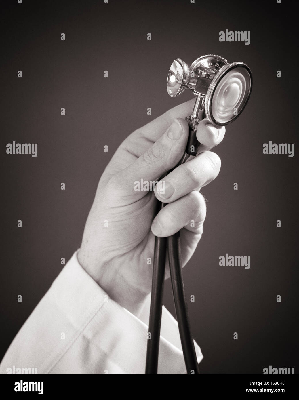 1960 homme médecin's hand holding a stethoscope - s15205 HAR001 HARS, MÉDECINS DE SOINS DE SANTÉ DE L'INNOVATION DIAGNOSTIC SÉVÈRE TRAITEMENT GUÉRISSEUR PROFESSIONS CONCEPT CONCEPTUEL VIE ENCORE PRATICIEN MÉDECIN CONCEPTS symboliques des professionnels de l'appareil NOIR ET BLANC DE L'ORIGINE ETHNIQUE CAUCASIENNE MAINS MALADIE SEULEMENT HAR001 REPRÉSENTATION À L'ANCIENNE Banque D'Images