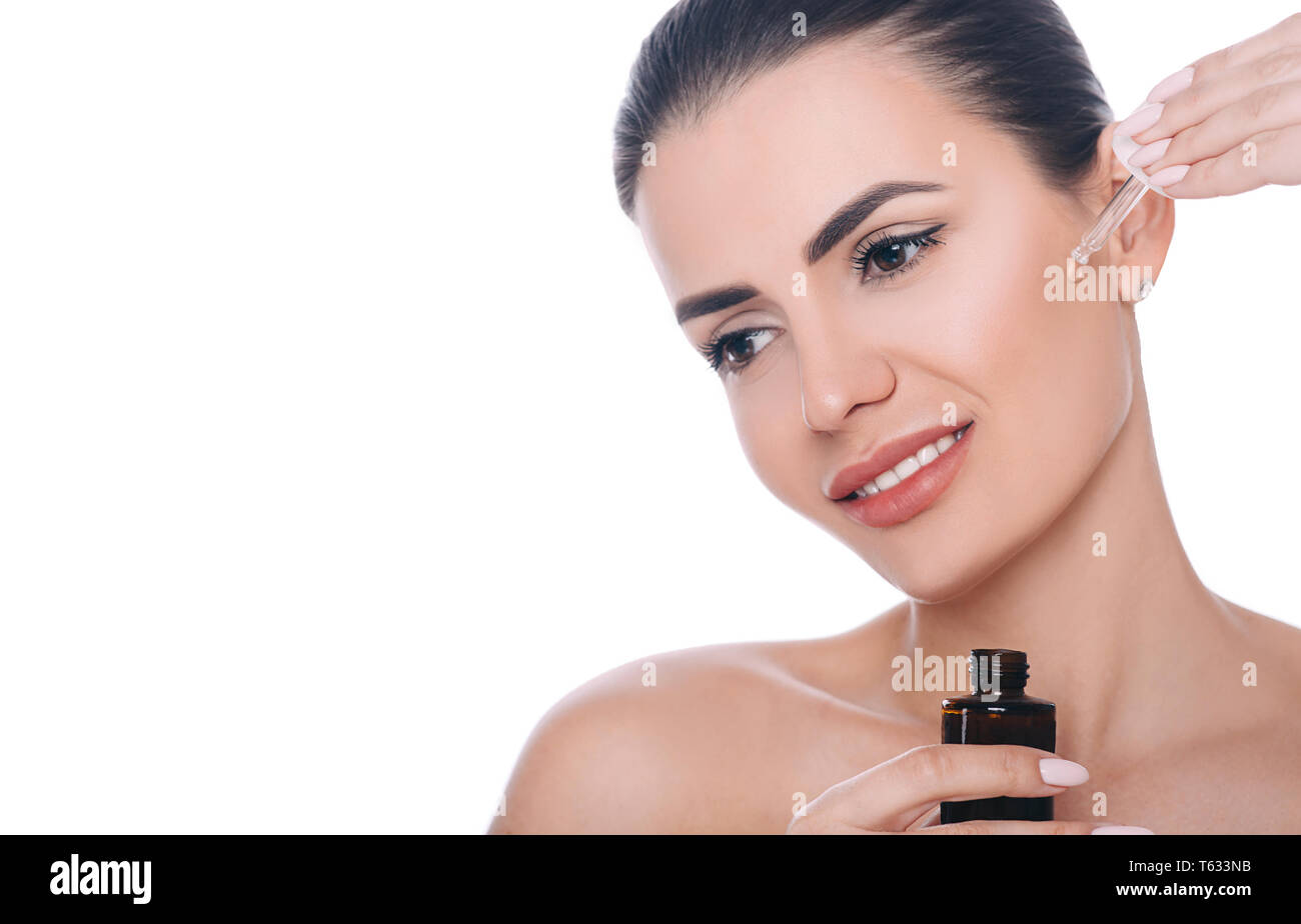 L'application de l'huile cosmétique femme sur le visage. Hydrater la peau sèche, soin de beauté Banque D'Images