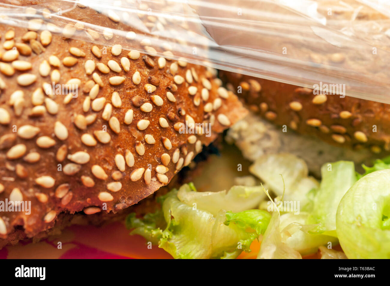 Burgers, laitue sur plaque rouge sous un emballage en plastique. L'entreposage des aliments à emporter, des idées. Banque D'Images