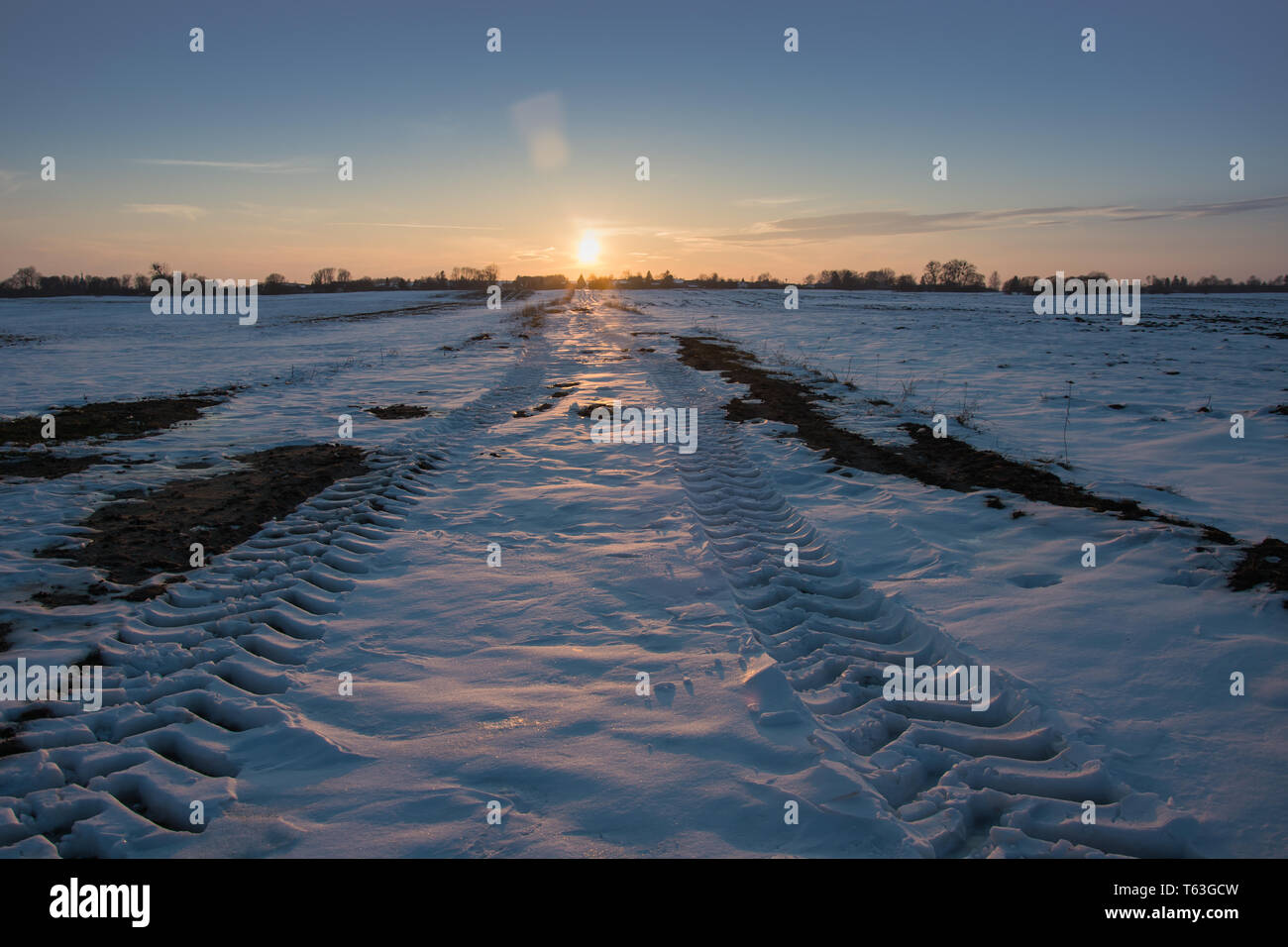 Traces de roues sur une piste enneigée, horizon et le coucher du soleil - vue d'hiver Banque D'Images