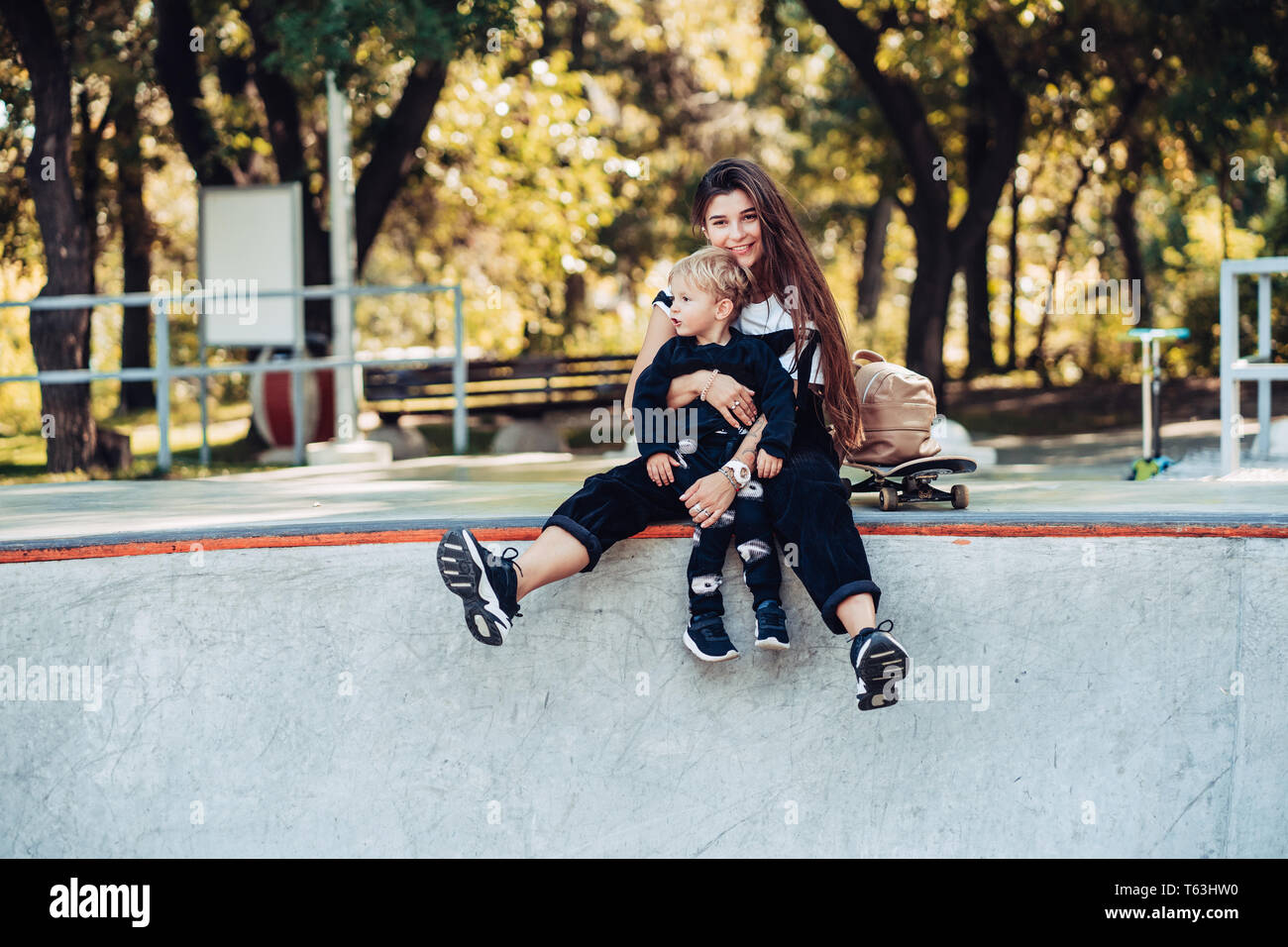 Belle jeune hipster maman et petit fils à l'skatepark Banque D'Images