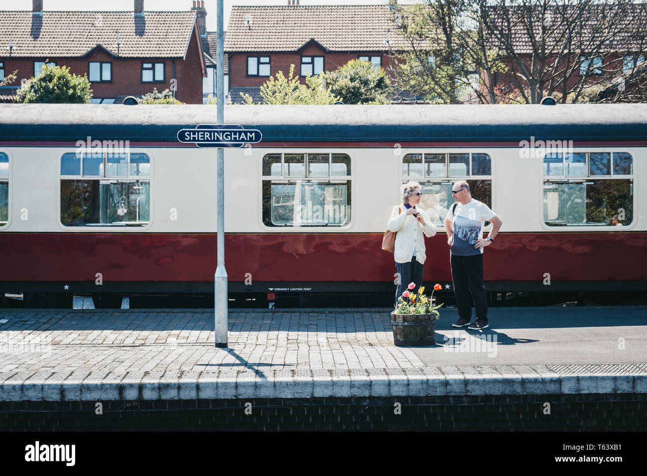 Sheringham, UK - 21 avril, 2019:Deux personnes debout sur une plate-forme du train à Sheringham, le coquelicot, un train de la ligne de chemin de fer à vapeur du patrimoine qui s'exécute à partir de S Banque D'Images