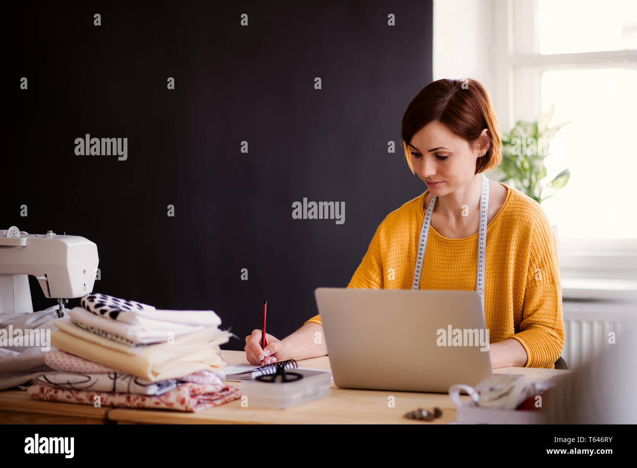 Creative young woman with laptop travaillant dans un studio, le démarrage de petites entreprises. L'adaptation. Banque D'Images