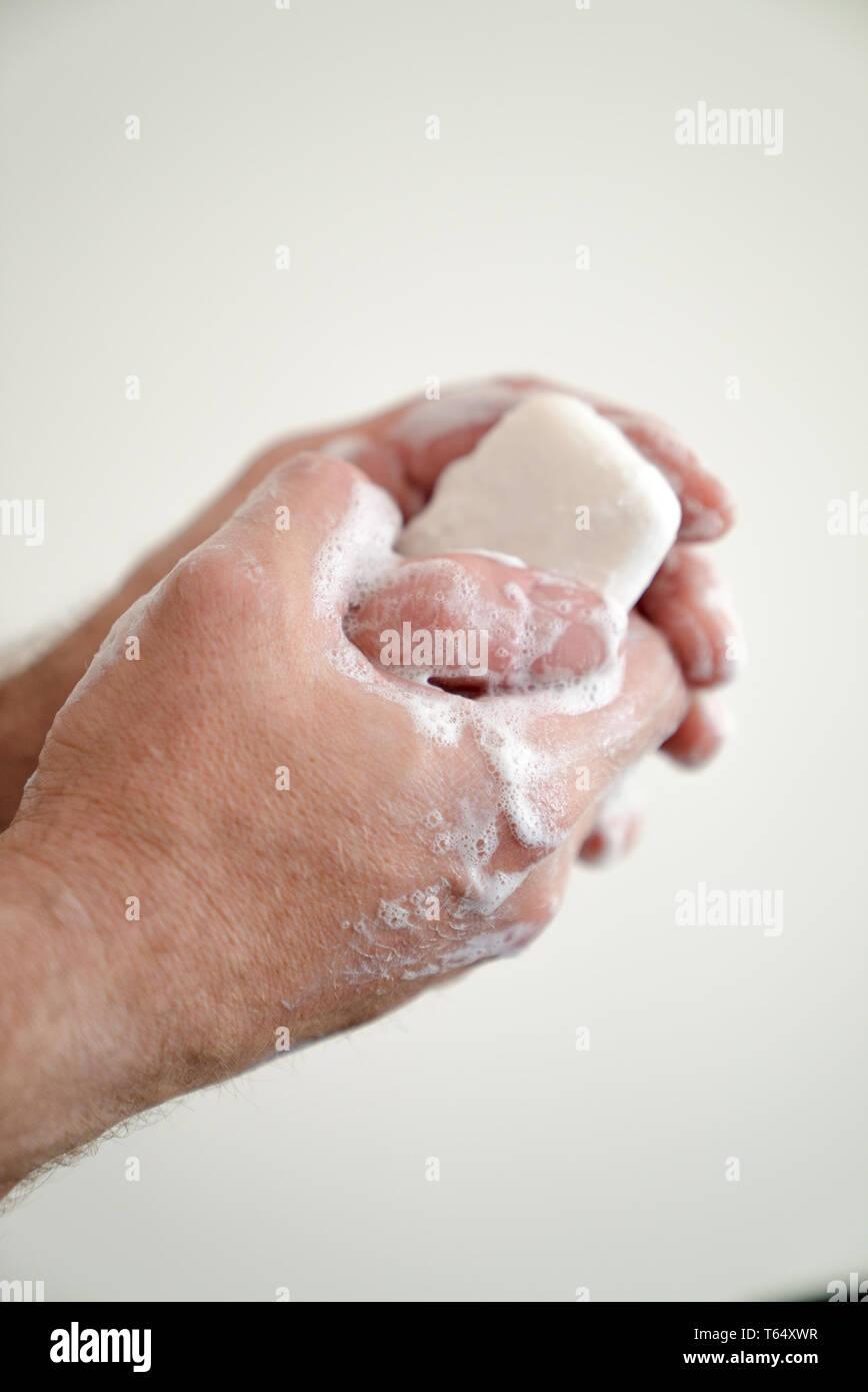 Close up of male les mains avec un savon et la mousse savonneuse sur fond blanc Banque D'Images