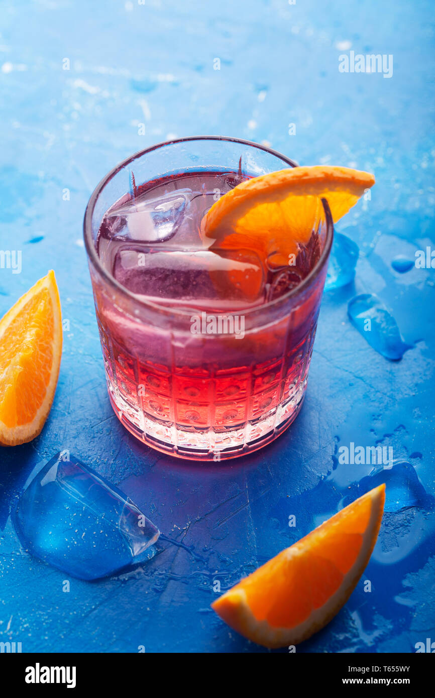 Glace fraîche plateau cocktail à l'orange et de la glace en verre sur fond bleu, orientation verticale Banque D'Images