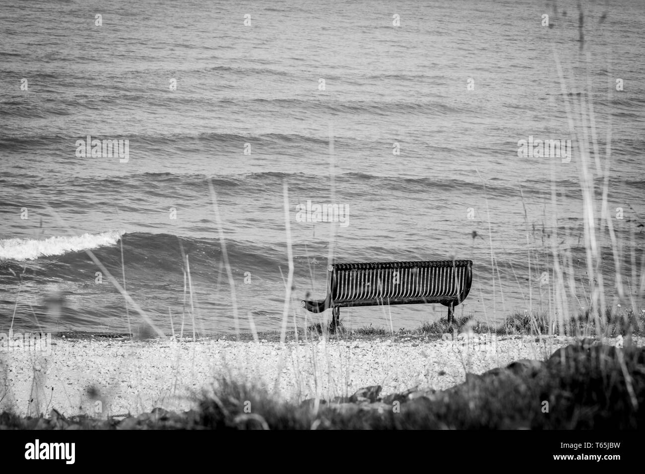 Noir et blanc photo de paysage par la mer avec lonely, banc vide. Banque D'Images