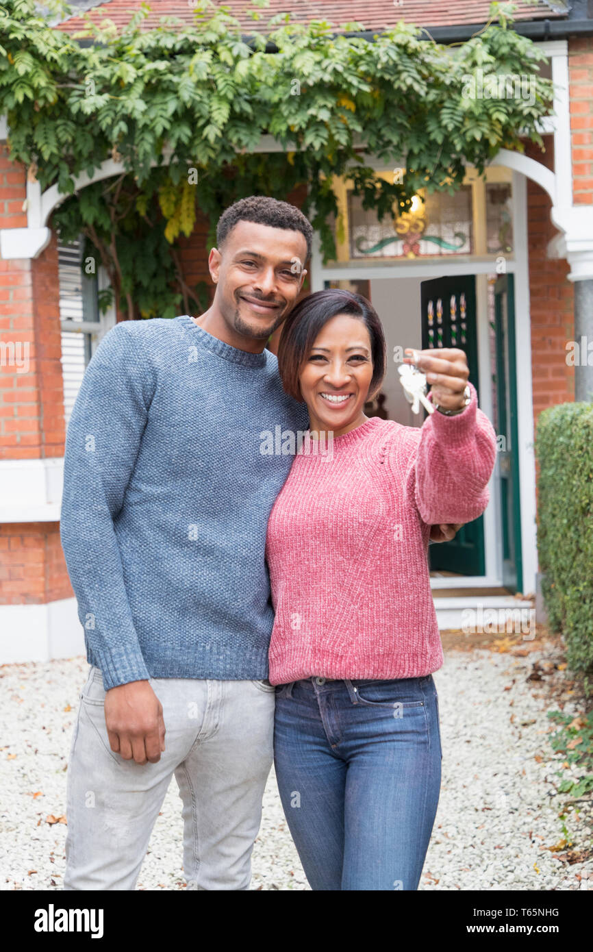 Portrait heureux couple holding clés de maison extérieur maison neuve Banque D'Images