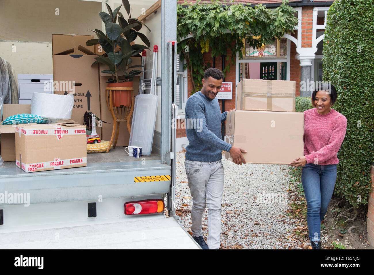 Couple déménagement hors de la maison, chargés de boîtes de camion de déménagement Banque D'Images