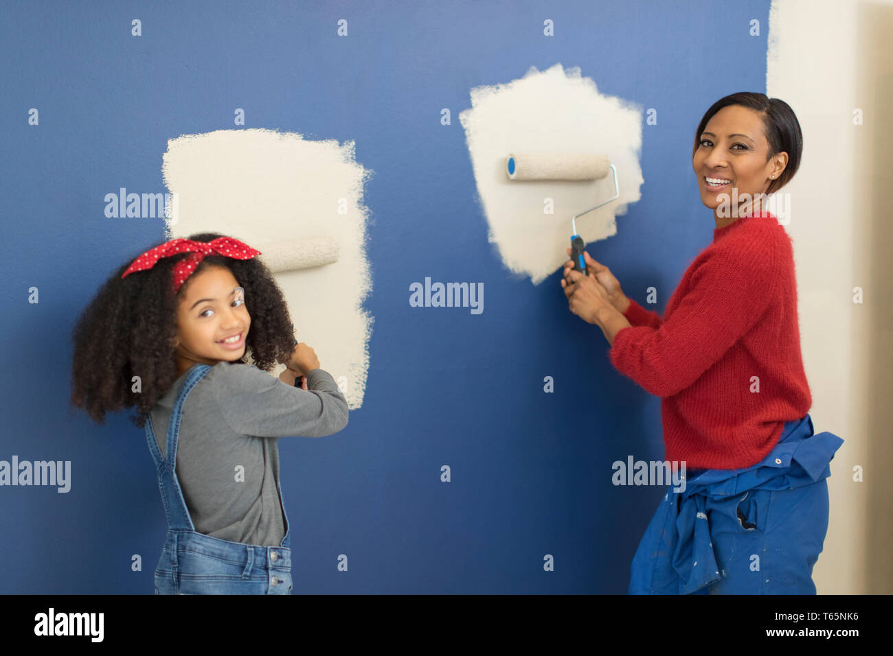 Portrait happy mother and daughter painting wall Banque D'Images