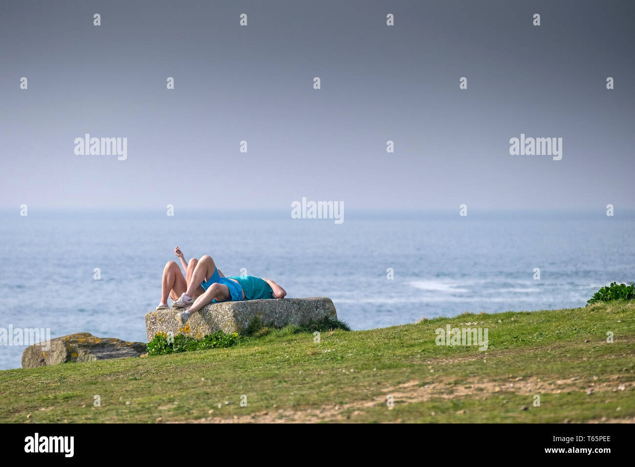 Vacanciers en vacances de vacances sur un rocher sur la côte à Fistral à Newquay en Cornouailles. Banque D'Images