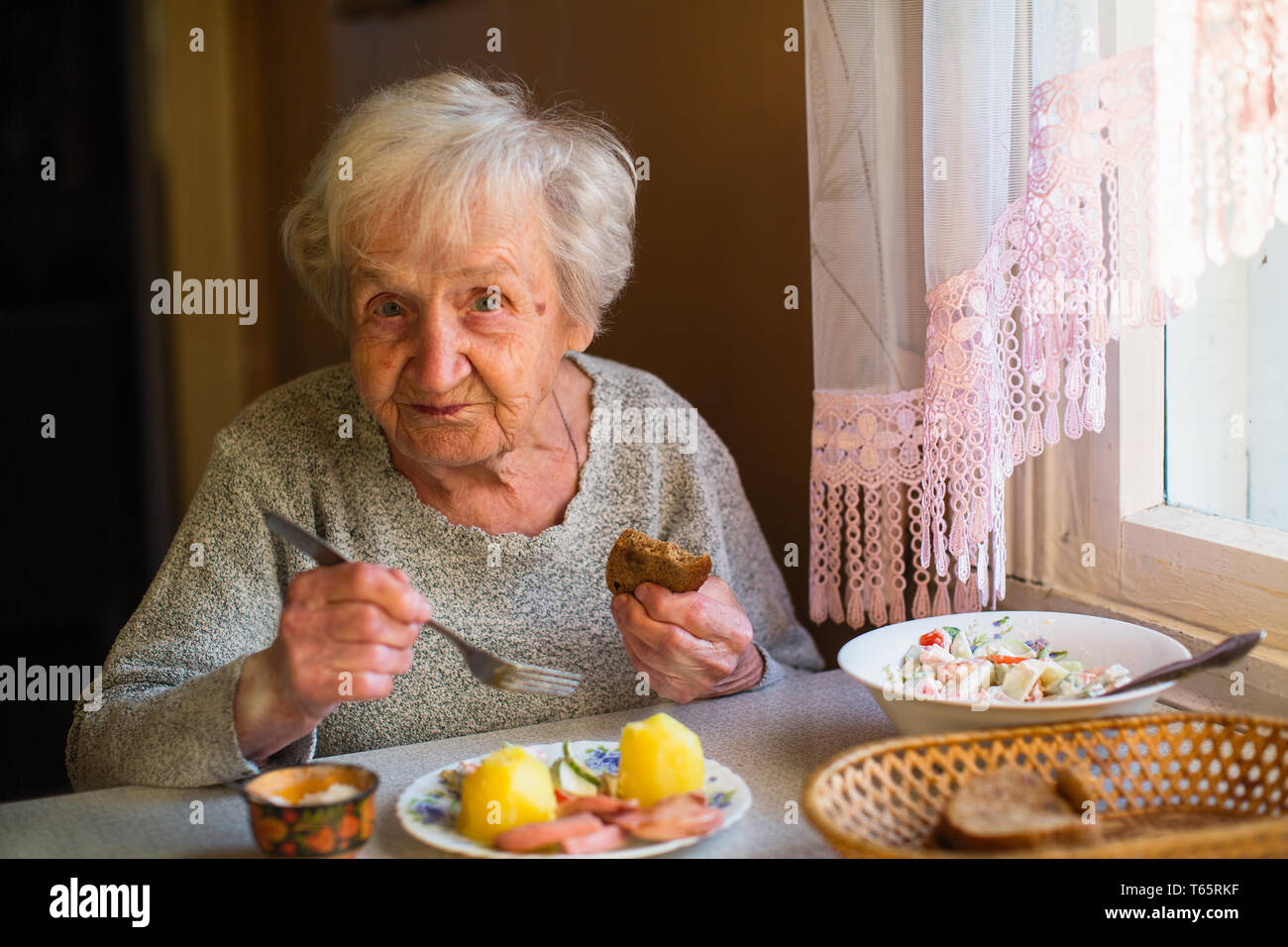 Une vieille femme est en train de dîner assis à une table dans sa chambre. Des soins pour les personnes âgées et les pensionnés. Banque D'Images