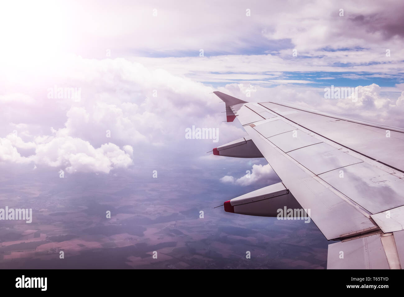 Vue d'une aile d'avion gris par la fenêtre de l'avion. Soleil, le réchauffement climatique. Banque D'Images