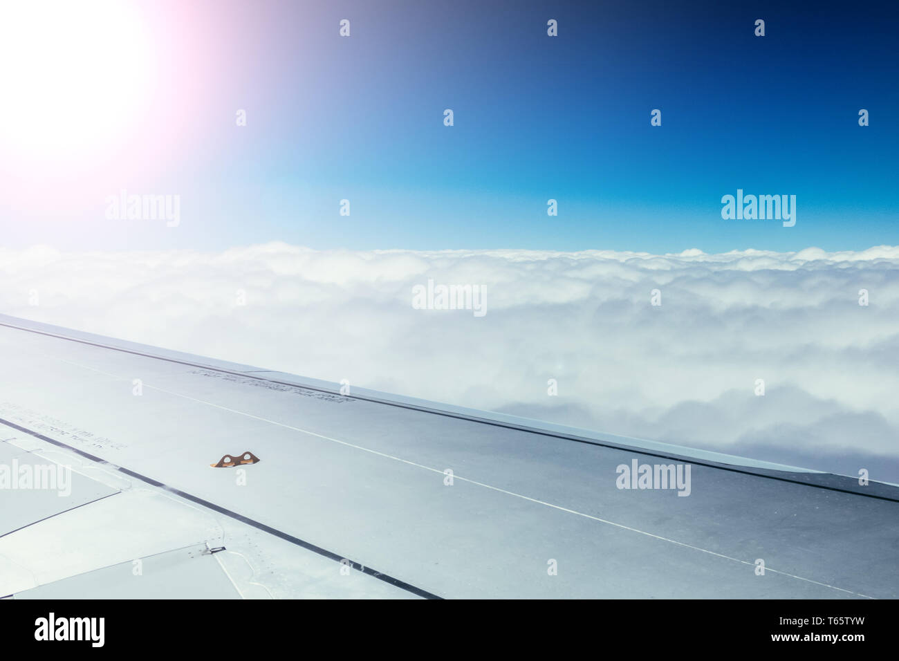 Vue d'une aile d'avion gris par la fenêtre de l'avion. Soleil, le réchauffement climatique. Banque D'Images