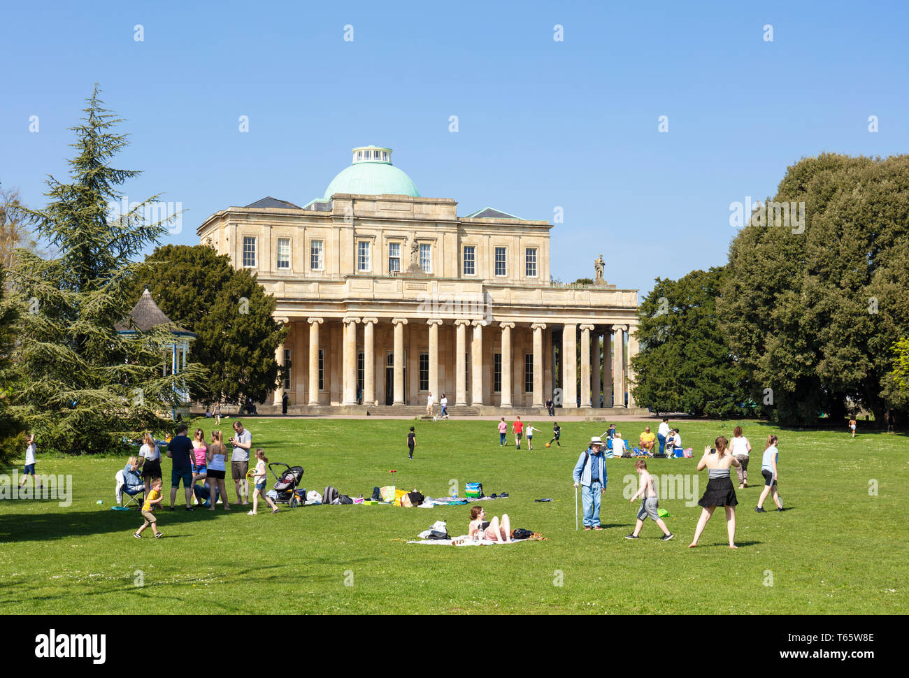 Cheltenham Pittville Pump room avec des gens ayant un pique-nique et des enfants jouer Pittville Park Cheltenham Spa, Gloucestershire, Angleterre, RU, FR, Europe Banque D'Images
