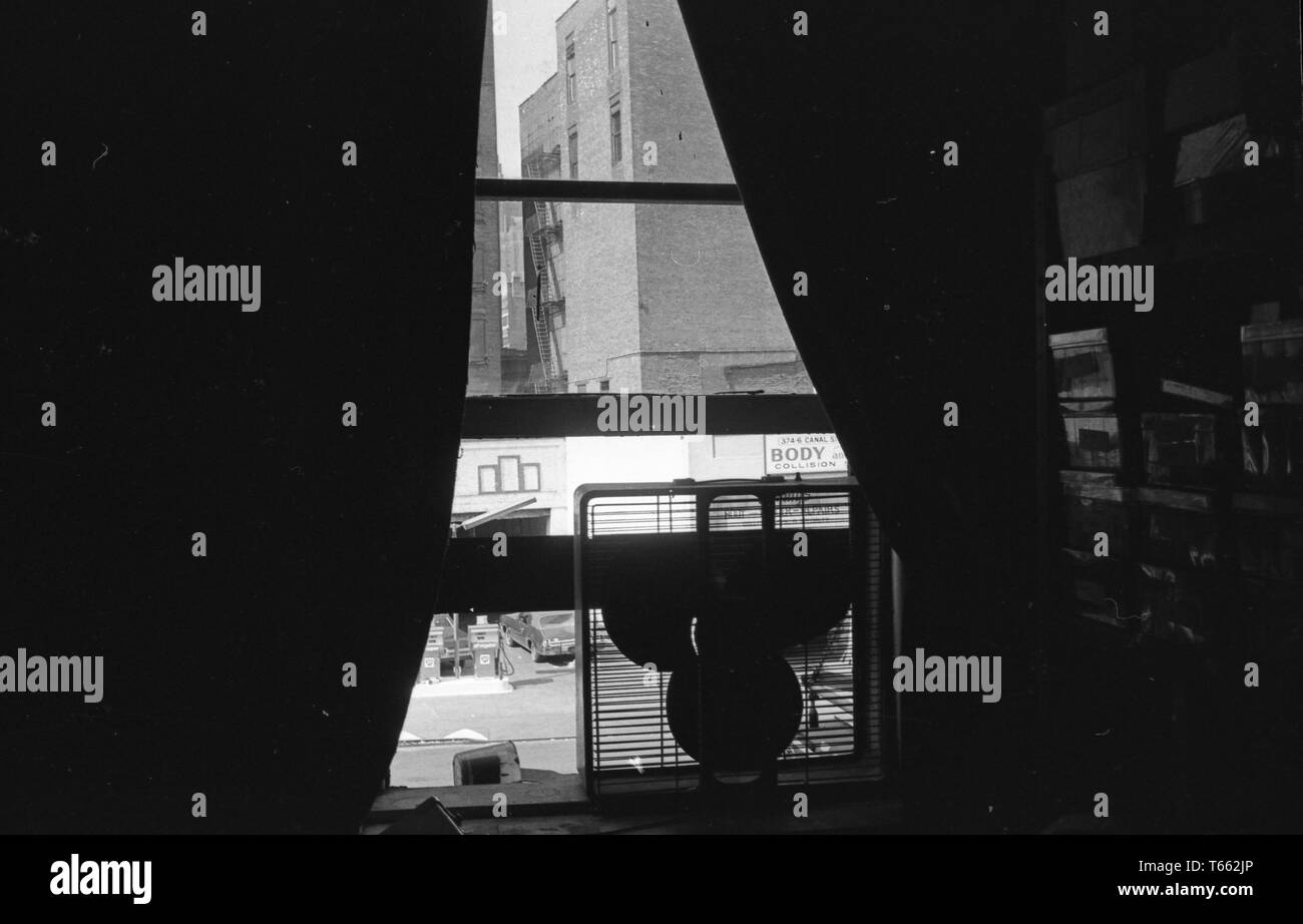 Portrait d'une rue de la ville, dans la perspective d'une histoire fenêtre avec rideaux partiellement ouvert et un ventilateur électrique perché sur le rebord de la vitre, Washington, District de Columbia, le 9 mai 1970. () Banque D'Images