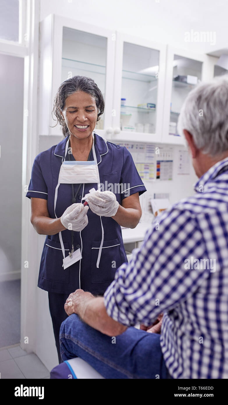 Femme médecin de prendre la tension artérielle de senior male patient en salle d'examen clinique Banque D'Images