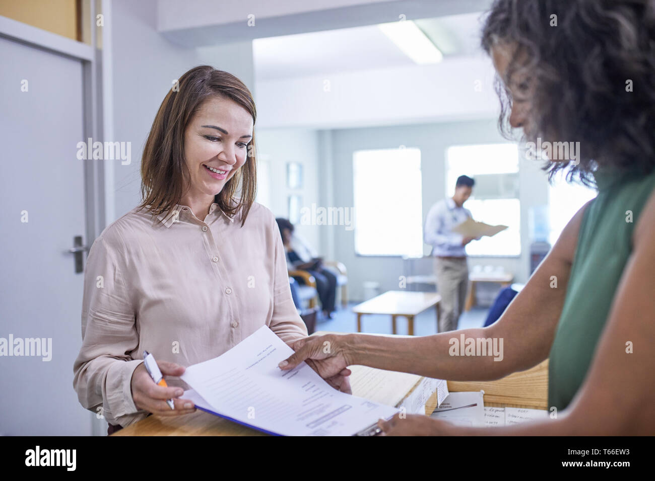 Aider réceptionniste femme avec des formalités administratives de la réception de la clinique Banque D'Images Aider réceptionniste femme avec des formalités administratives de la réception de la clinique Banque D'Images