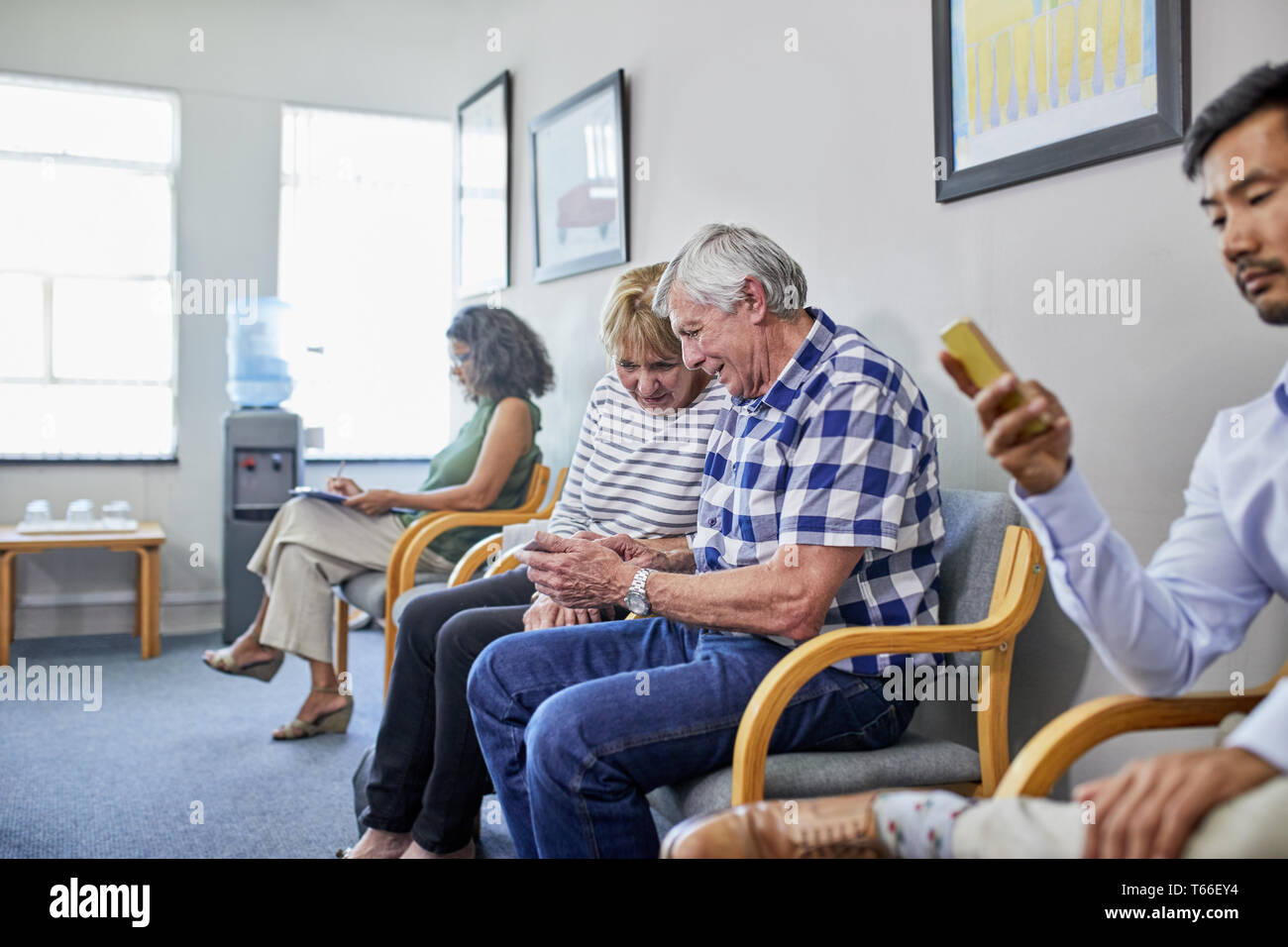 Couple using smart phone en salle d'attente de la clinique Banque D'Images