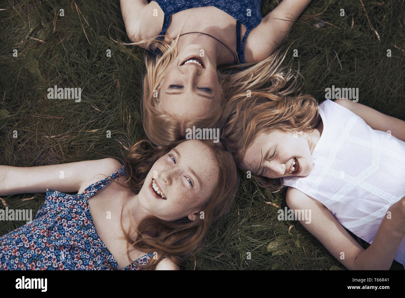 Portrait heureux sisters laying in grass Banque D'Images