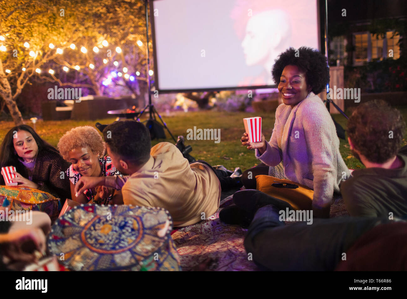 Friends eating popcorn, profitant de film sur l'écran de projection in backyard Banque D'Images