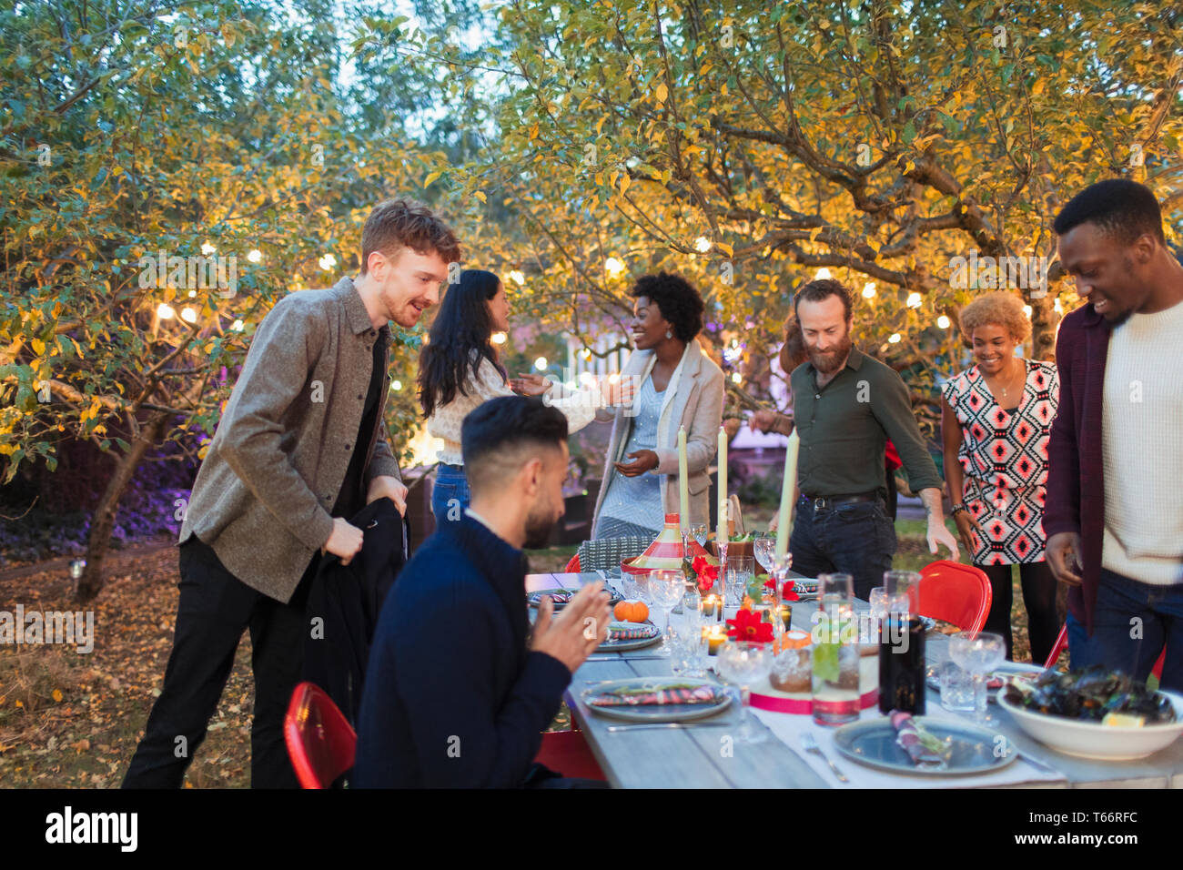 L'arrivée d'amis, assis pour le dîner garden party Banque D'Images
