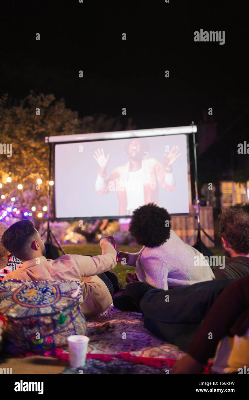 Les amis regarder la vidéo sur l'écran de projection in backyard Banque D'Images