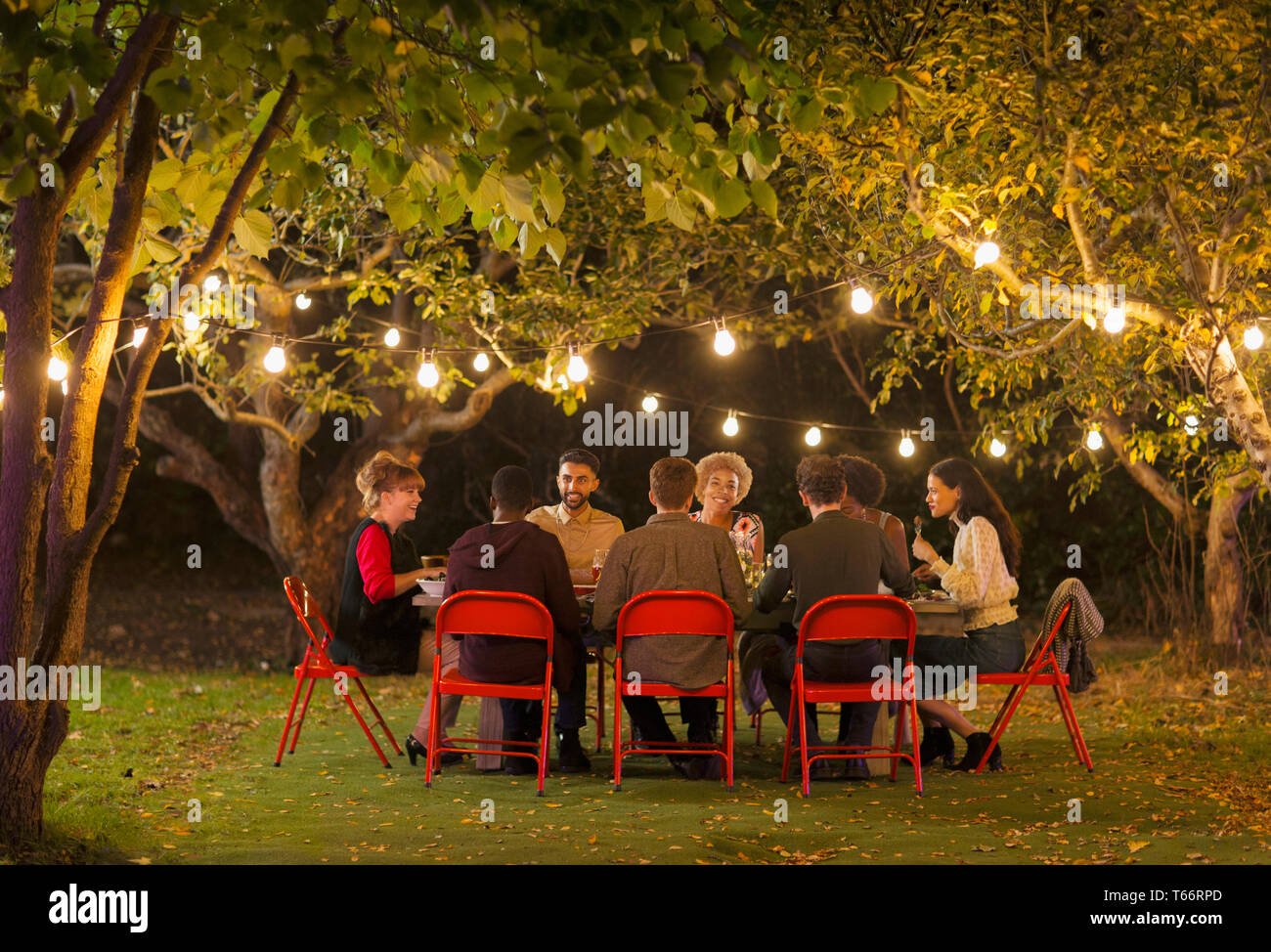 Les amis de dîner garden party sous les arbres avec fairy lights Banque D'Images