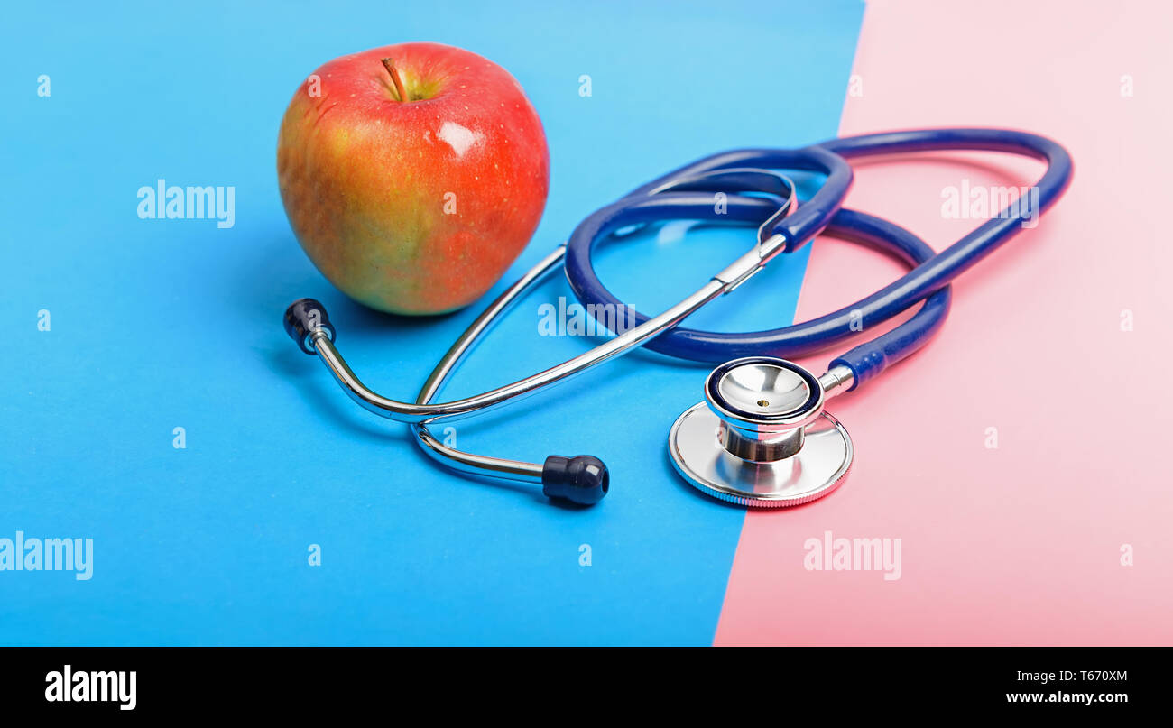 Stéthoscope et apple entre le bleu et le rouge, le concept de la frontière de la santé et de la maladie, en bonne santé et mode de vie malsain. Banque D'Images