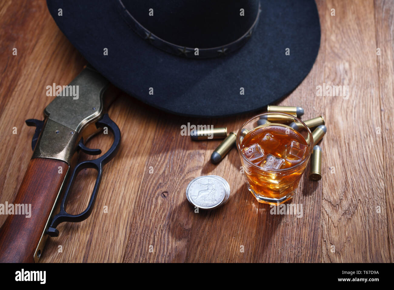 Wild West et de munitions de fusil avec verre de whisky et de la glace avec de vieux silver dollar sur table bar en bois Banque D'Images