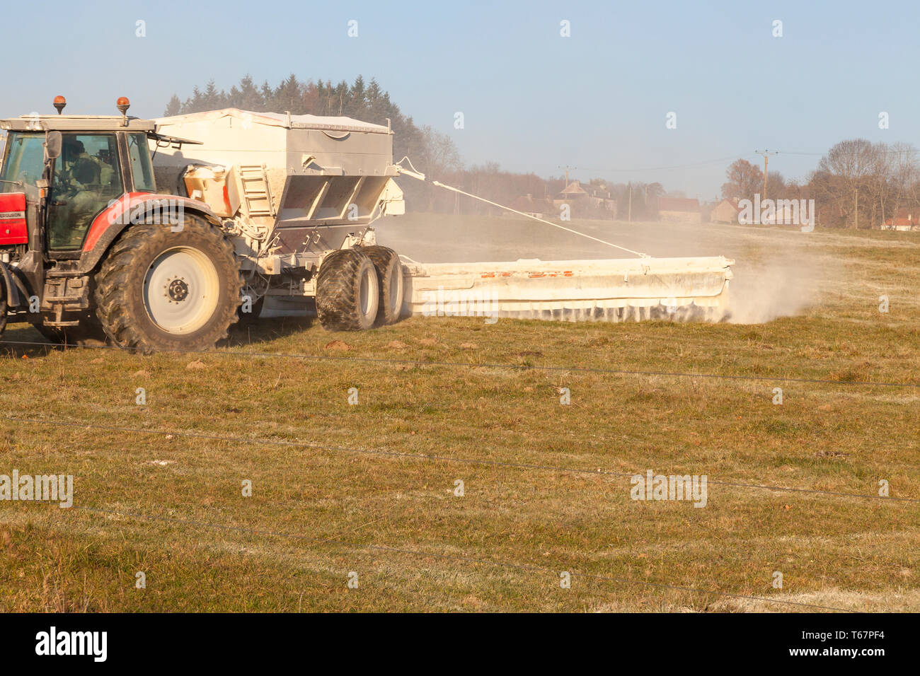 À l'aide d'un agriculteur de l'épandeur de produit chimique sur un tracteur pour féconder un pâturage pendant l'hiver pour ses animaux, d'engrais chimiques, d'herbe de pâturage près u Banque D'Images