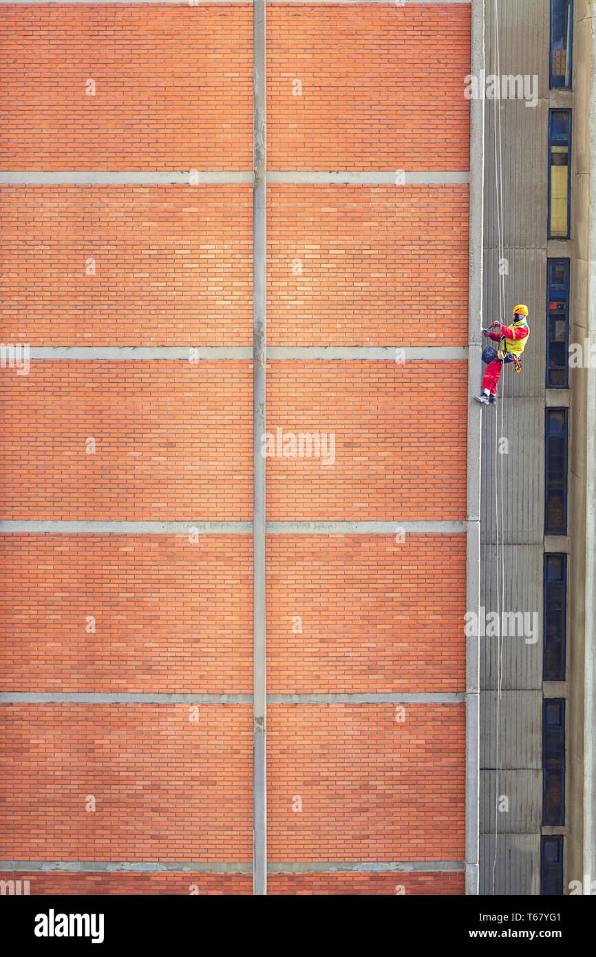 Les travailleurs de la construction sont travaillant dans des capacités. Pour la construction et réparation façade de briques. - Image Banque D'Images