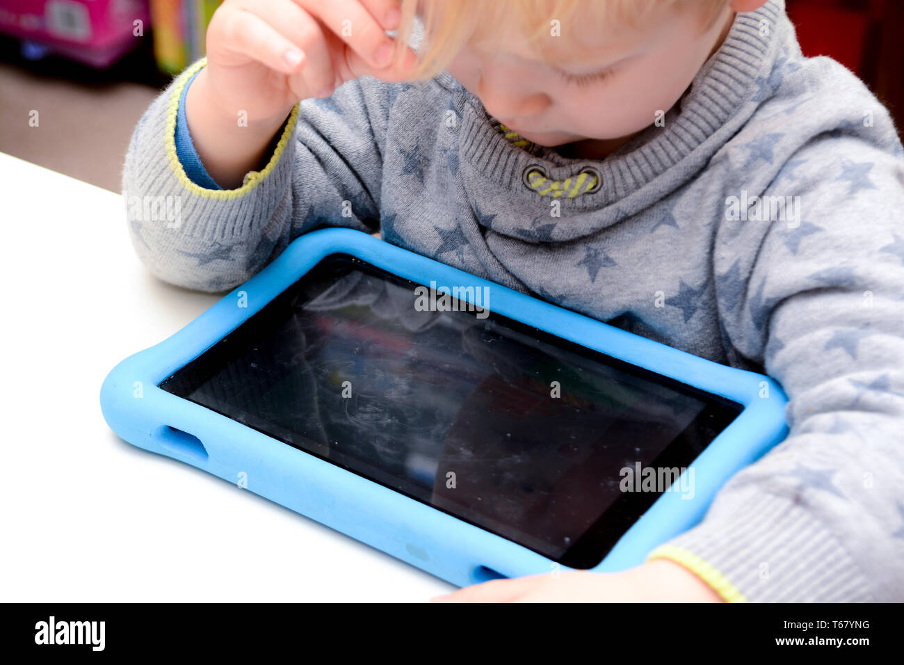 Le jeune enfant est heureux à l'aide d'un ordinateur tablette. Garçon joue avec l'appareil à la maison sur canapé Banque D'Images