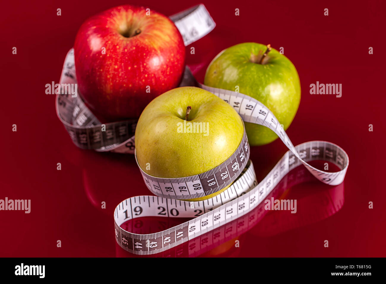 Les pommes avec ruban à mesurer sur fond rouge. Notion de perte de poids Banque D'Images
