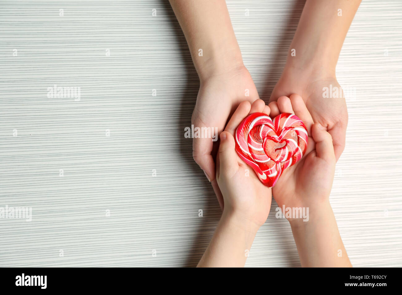 Les mains de la mère et l'enfant avec des bonbons en forme de cœur sur fond clair Banque D'Images