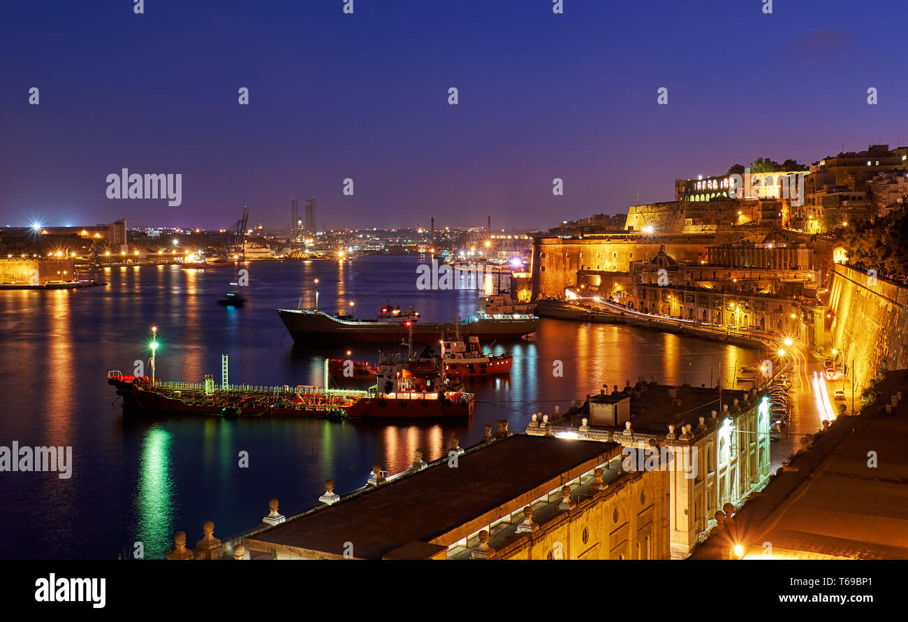 La vue de nuit Grand Harbour avec les cargos amarrés près de Saint Barbara Bastion, La Valette. Banque D'Images