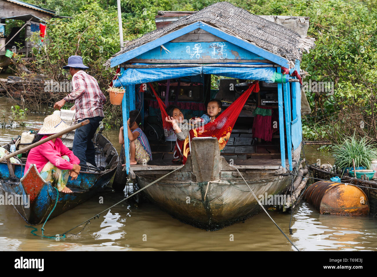 Gros plan du petit bleu bateau maison sur bord de jungle en rivière avec trois enfants et les parents Banque D'Images