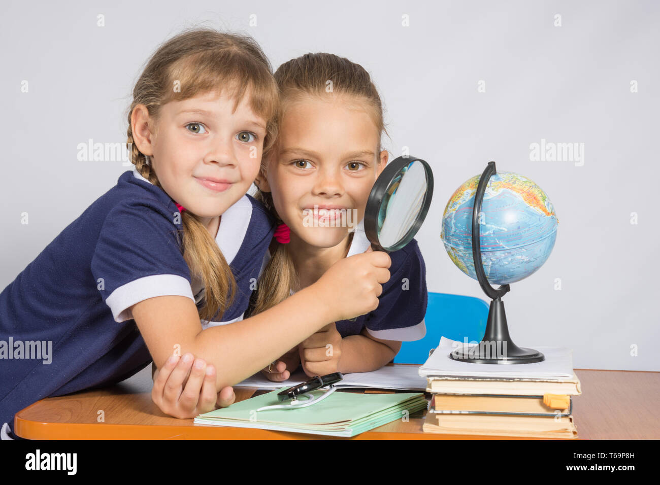 Deux écolières looking at globe à travers une loupe Banque D'Images